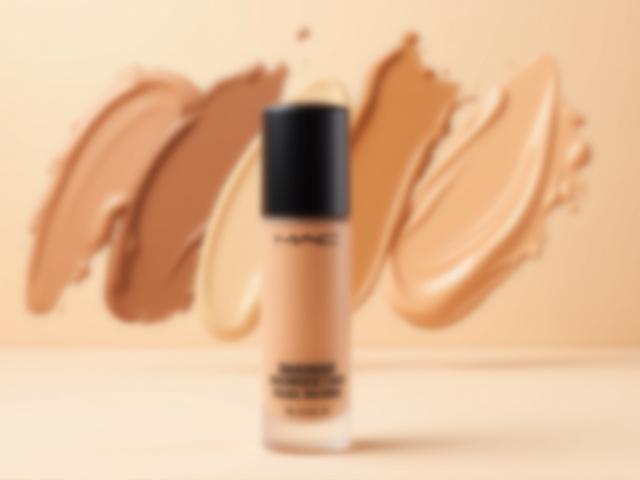 M·A·C Studio Fix Fluid foundation bottle with diverse shade range swatches in the background.